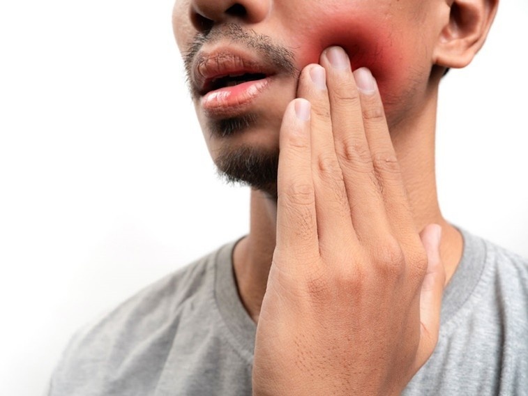 Person holding swollen cheek from tooth pain